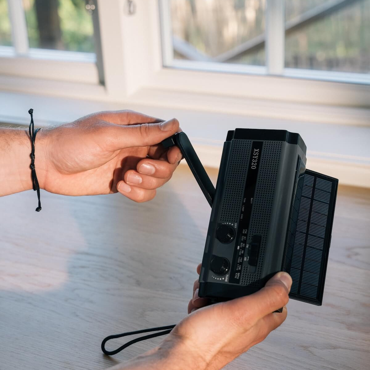 Person, der holder Bereds Vevradio med 4500 mAh batteri, solceller, håndsving og USB-C-opladning