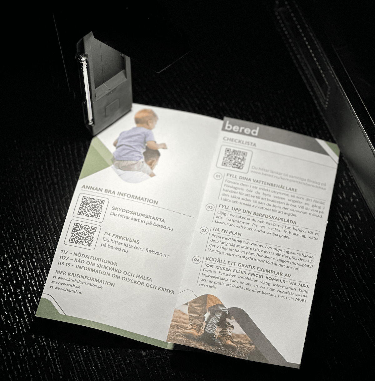 En foldet brochure med beredskabsinformation, tjeklister og kontaktoplysninger på en mørk baggrund.