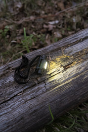 En ung man i mörkret lyser upp sitt ansikte med en pannlampa.