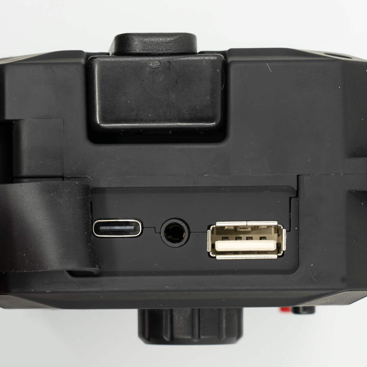 Nærbillede af tilslutningsportene (USB-C, hovedtelefonstik, USB-A) på en sort nødradio.