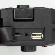 Nærbillede af tilslutningsportene (USB-C, hovedtelefonstik, USB-A) på en sort nødradio.