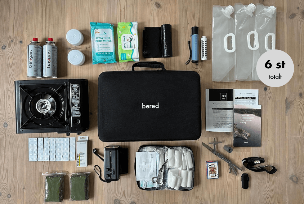 En stor bild av ett hemberedskapskit med gasolkök, hygienartiklar, nödradio, vattenbehållare, första hjälpen-kit med mera.