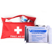 Et sort redningstæppe med påskriften "EMERGENCY RESCUE BLANKET" ligger i en åben rød førstehjælpskasse.