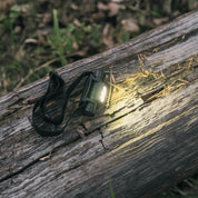 En upplyst svart pannlampa som ligger på en trädstam.