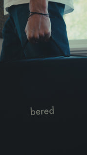 En närbild av en hand som håller i en svart väska med ordet “bered” på.