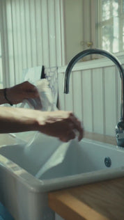 En person som fyller en genomskinlig plastpåse med vatten från en köksblandare.