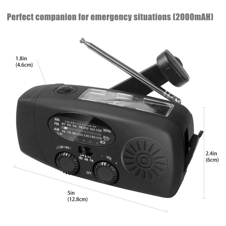 En svart vevradio med solpanel och ficklampa, med ett utfällt vevhandtag, som ligger på ett träbord.
En svart nödradio med solpanel, utfällbar vev och måttangivelser, texten "Perfect companion for emergency situations (2000mAh)" ovanför.