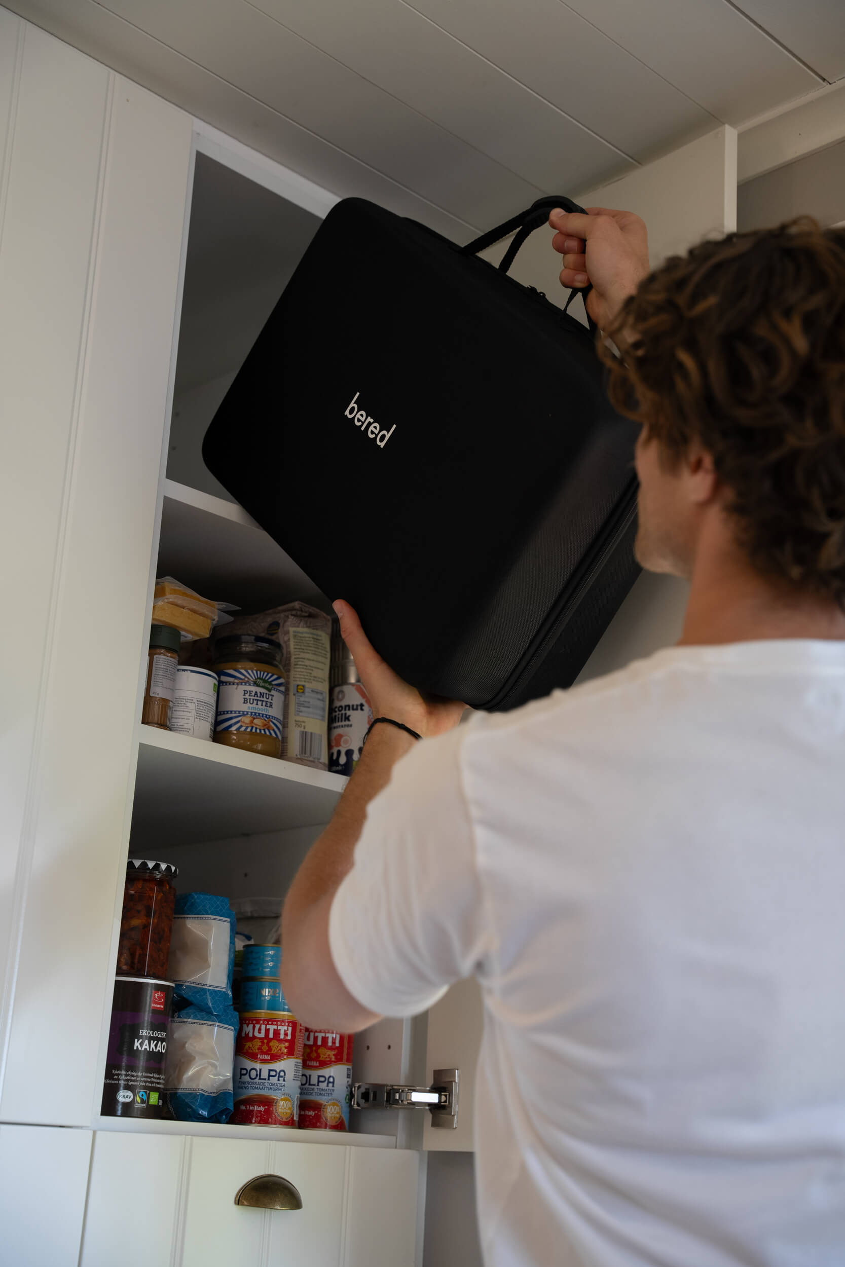En person lägger in en svart beredskapslåda med texten "bered" i ett skåp.