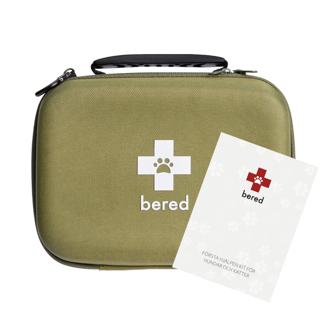 Ett beige första hjälpen-kit för husdjur med en lapp bredvid som förklarar dess innehåll.